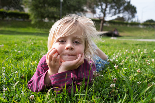 Summer Serenity: Little Girl Relaxing and Dreaming on Green Grass in a City Park