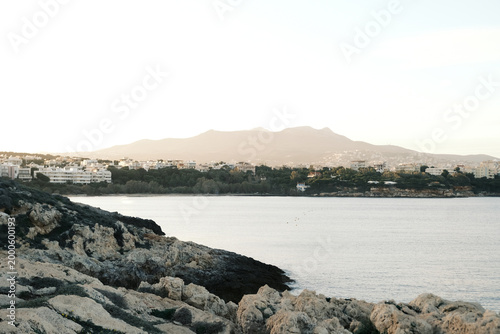Coastal town nestled between rocky shores and distant mountains at sunrise