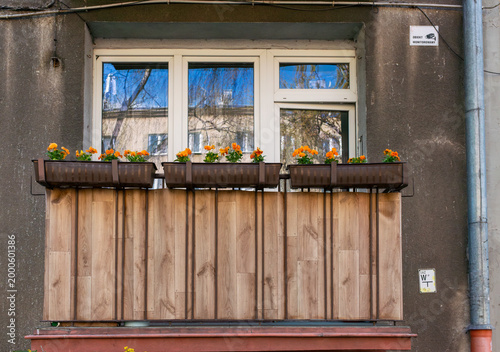 Tableau sur toile Residential window with wooden balcony panels and flower boxes planted with orange pansies