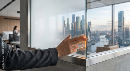 Hand interacting with futuristic transparent smart screen displaying honeycomb pattern in modern office cityscape.