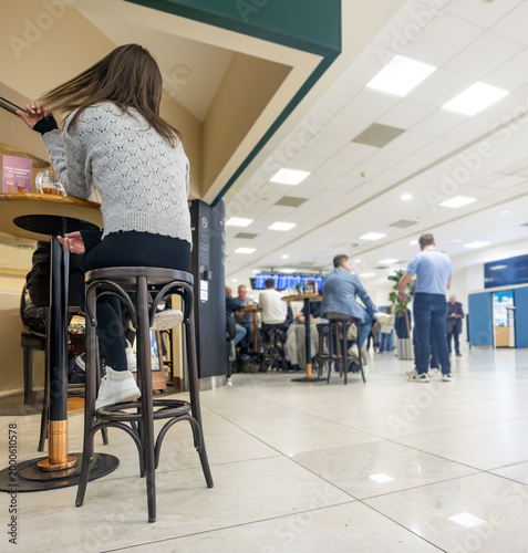 Rear View of Woman Traveler Sitting at Airport Cafe Counter Waiting for Departure