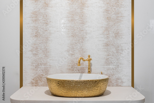 Stylish ceramic golden sink and faucet on bathroom counter Designer bathroom sink with gold faucet and decorative basin placed on modern vanity in luxury interior