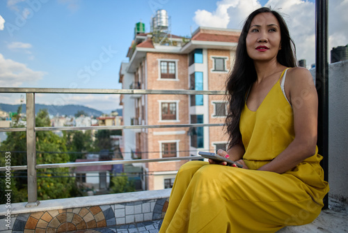 Female model in golden dress seated on ledge direct eye contact confident and composed look