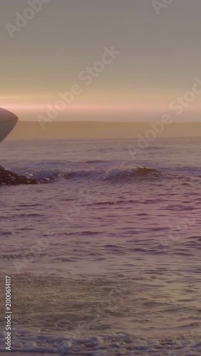 Vertical video: Board entering, surfer walking shore with board post-surf, motion splashes sports
