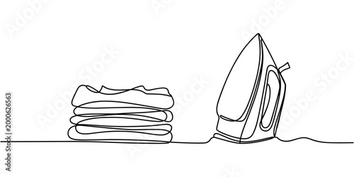 Single line of a household electric iron next to a stack of folded clothes laundry ironing