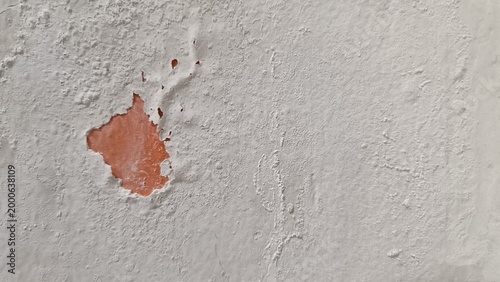 Fotografija A close-up view of a damaged wall with peeling paint exposing red surface underneath