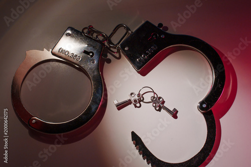Open handcuffs with keys under red light, justice concept