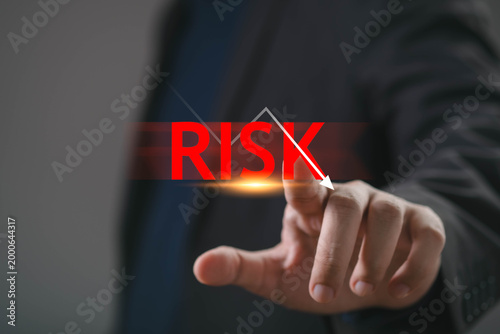 Businessman hand touching risk indicator with downward arrow representing financial loss, market volatility, investment uncertainty, crisis management, economic downturn and strategic risk assessment.