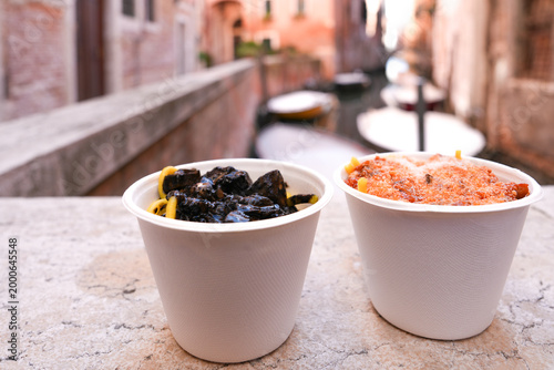 Takeaway italian pasta in paper cups with Venice canal and boats in the background