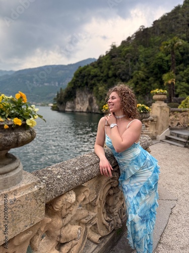 young woman in blue dress in Italy on bridge in April near mountains