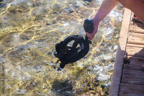 Woman cleaning her snorkeling mask in the clear blue sea, preparing exciting underwater adventure and enjoying the beauty of marine life.