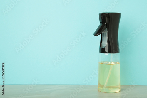 Cooking oil glass sprayer on blue background. Space for text