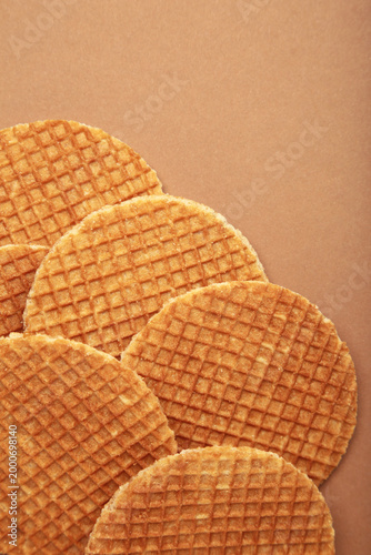 Dutch stroop wafel cookies or caramel waffles on brown background. Vertical photo