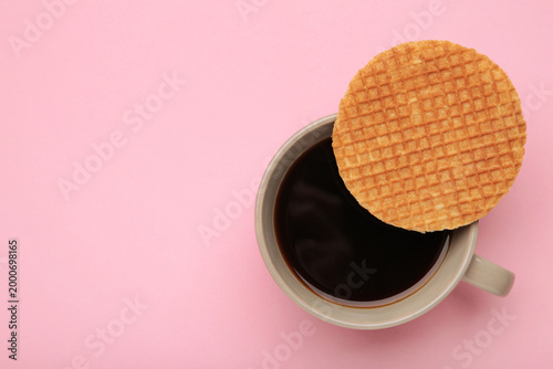 Traditional local authentic Dutch Netherlands sweet fresh homemade tasty stack brown golden waffle melt salted caramel with hot warm coffee. Stroopwafel on pink background