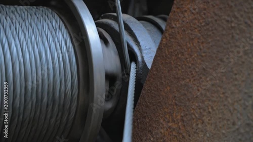 Engaging motor, drum rotating, braided cable sliding into sheave gap to seat cable in equipment bay