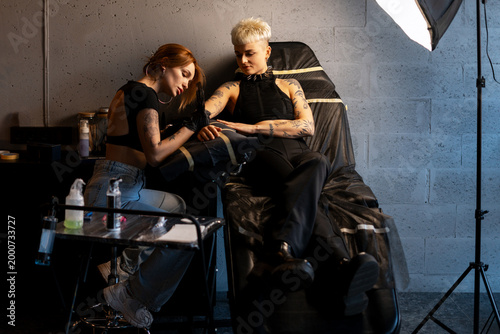 Photos Tattoo artist tattooing arm of female client in studio