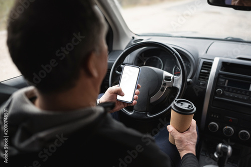 Driver Using Smartphone And Holding Coffee While Driving Car
