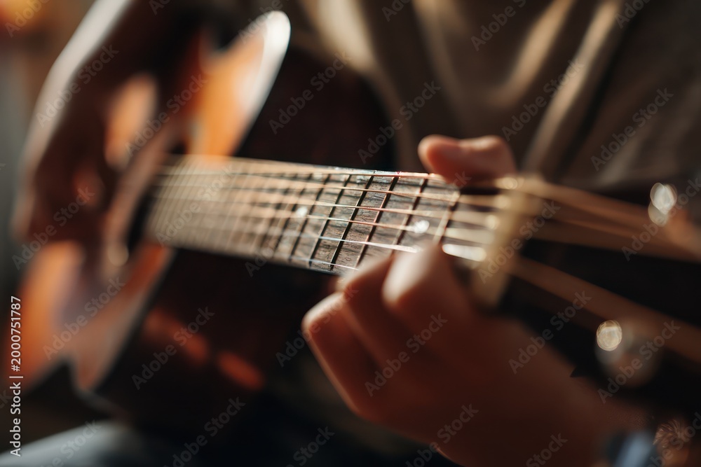 Fototapeta premium Boy's hands adjusting guitar tuning peg
