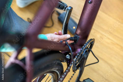Senior Woman Plugging in Electric Bicycle for Charging at Home Close-Up 