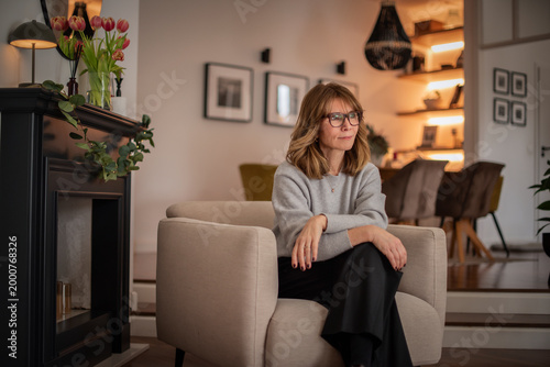 Blond haired attractive woman relaxing in an armchair in her modern apartment