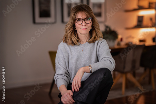 Blond haired attractive woman relaxing in an armchair in her modern apartment