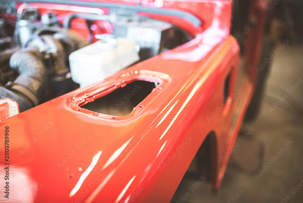 Fototapeta premium Shiny red car fender undergoing restoration in a workshop setting
