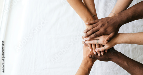 Cuadro en lienzo A diverse group of hands stacked together on a white surface, symbolizing unity, teamwork, and collaboration among individuals of different backgrounds