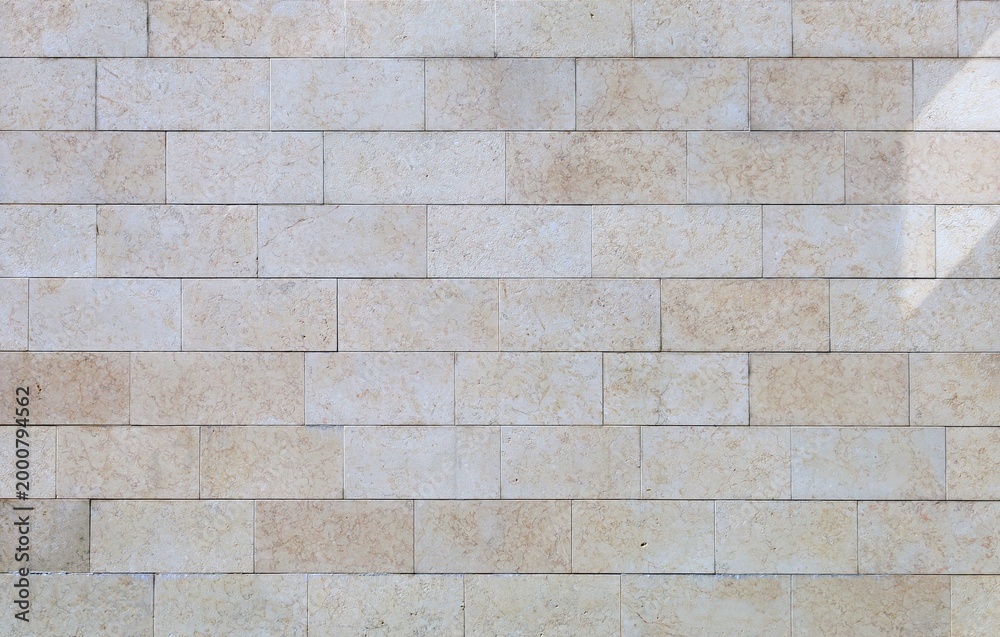 Fototapeta premium Off-white and beige travertine wall made of large rectangle tiles. Background and texture. Full frame.