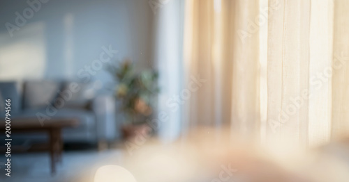 Fotografie A softly lit living room interior featuring a blurred view of curtains, a cozy sofa, and a plant, creating a serene and inviting atmosphere