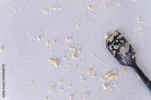 Tableau sur toile Scattered raw dough crumbs with black spatula on light kitchen surface, baking m