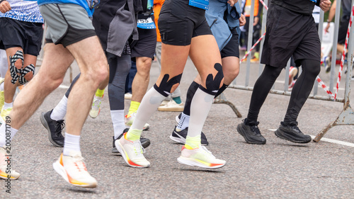 Bild auf Leinwand Athletes running on asphalt with sports injury support and colorful kinesio tape