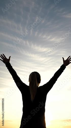 Lone figure with outstretched arms against a vibrant golden hour sky, bathed in warm light from a low angle, emphasizing joy and boundless potential concept of freedom and achievement