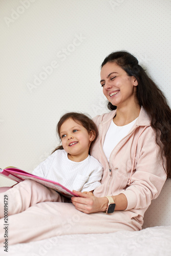 Mother and daughter sharing a happy moment reading a storybook, experiencing joyful childhood education and family bonding