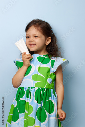 smiling child girl presenting children's sunscreen or moisturizer tube,