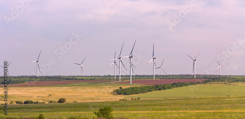 A small wind farm in the middle of agricultural fields in cloudy weather
