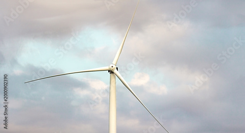 Close-up of a wind turbine generating clean energy against a cloudy sky. Renewable energy technologies in a peaceful outdoor setting
