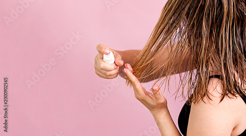 close-up of a woman's hands applying hair conditioner to wet hair