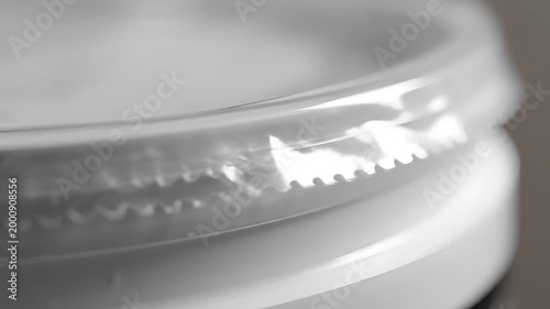 Closeup of a white plastic container lid with a clear plastic seal.