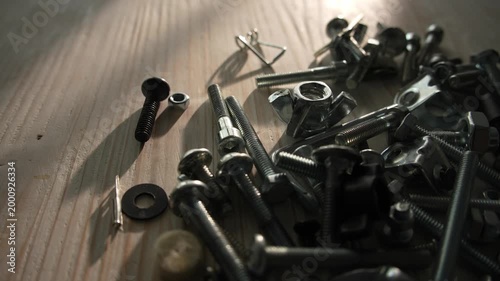Scattered metal bolts and screws on wooden surface in sunlight