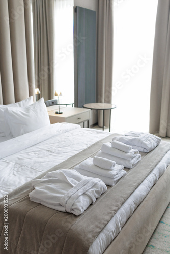 Hotel bed with towels near window light