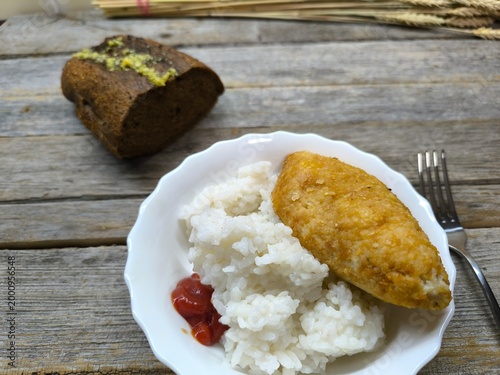 Kyiv cutlet with white rice on a plate on a wooden table