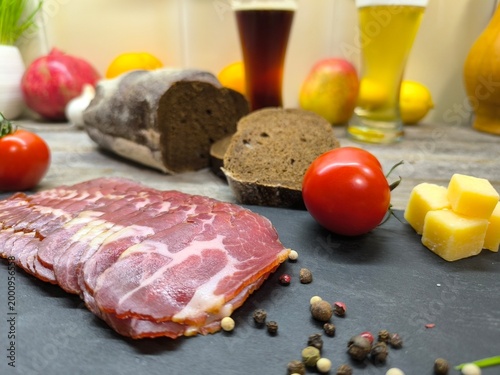 Thin slices of bacon lie on a sliced board in the background of a beer tank