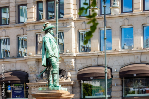 Oslo, Norway - May 17, 2025: Historic bronze statue of King Karl Johan standing in central Oslo with elegant classic buildings and city architecture in the background on a bright spring day.