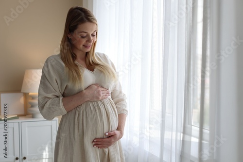 Pregnant woman touching her belly near window at home Free Download Pregnant woman touching her belly near window at home - GFXLoad