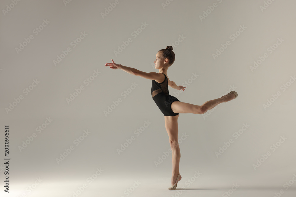 Naklejka premium Cute little girl doing gymnastic exercise on white background