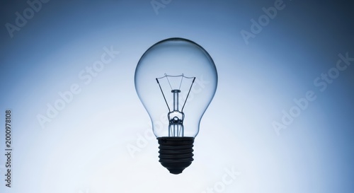 A clear light bulb on a gradient blue background with a black base and filament