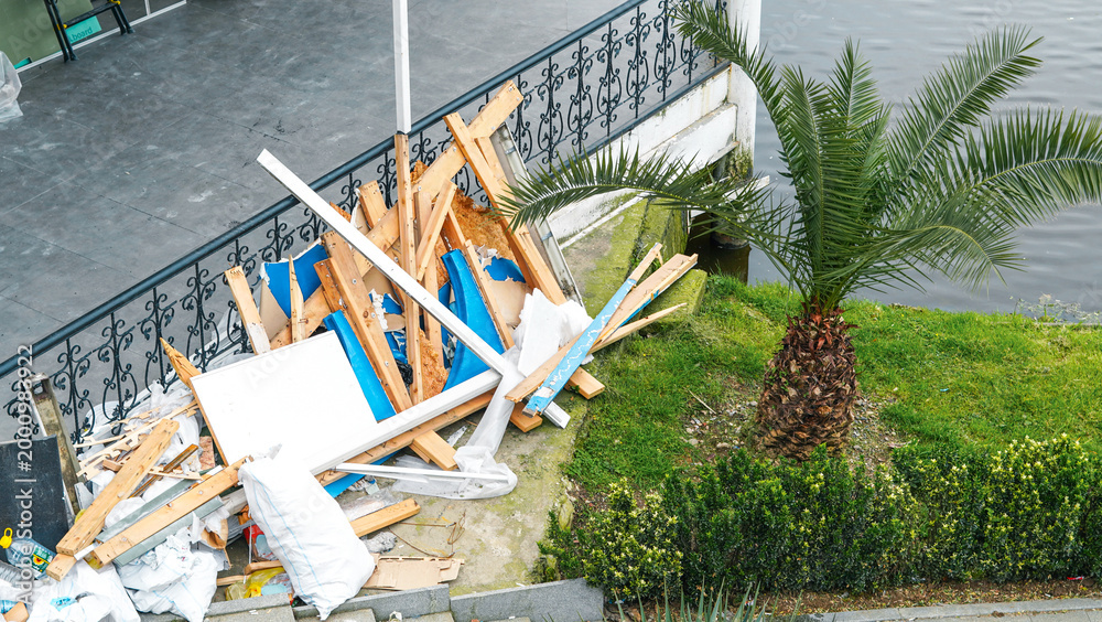 Fototapeta premium Pile of construction debris near palm tree by waterfront area