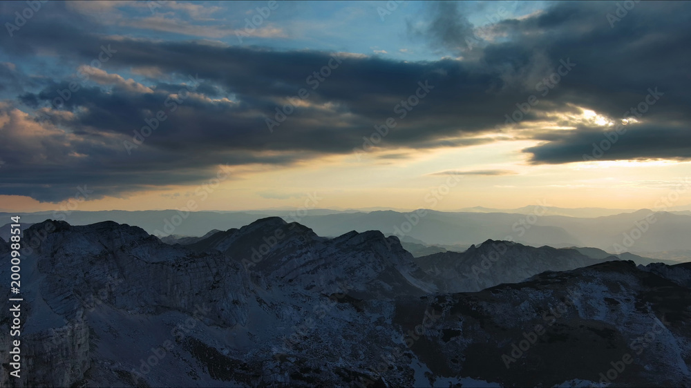 Obraz premium Sunset over mountain with dramatic clouds