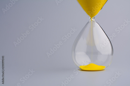 An hourglass counting down against a gray background symbolizes working with time and using it as efficiently as possible.