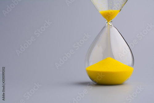 An hourglass counting down against a gray background symbolizes working with time and using it as efficiently as possible.